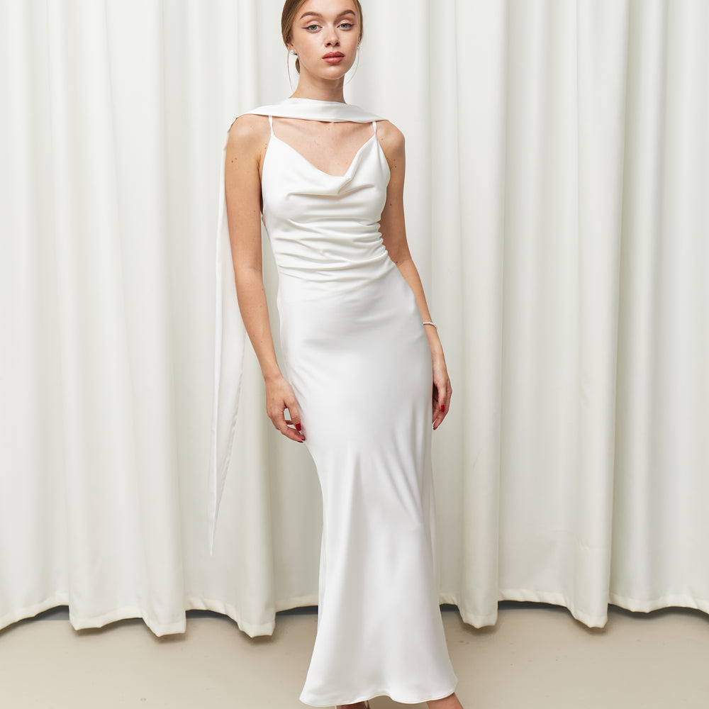 Woman wearing a white dress standing against a white curtain